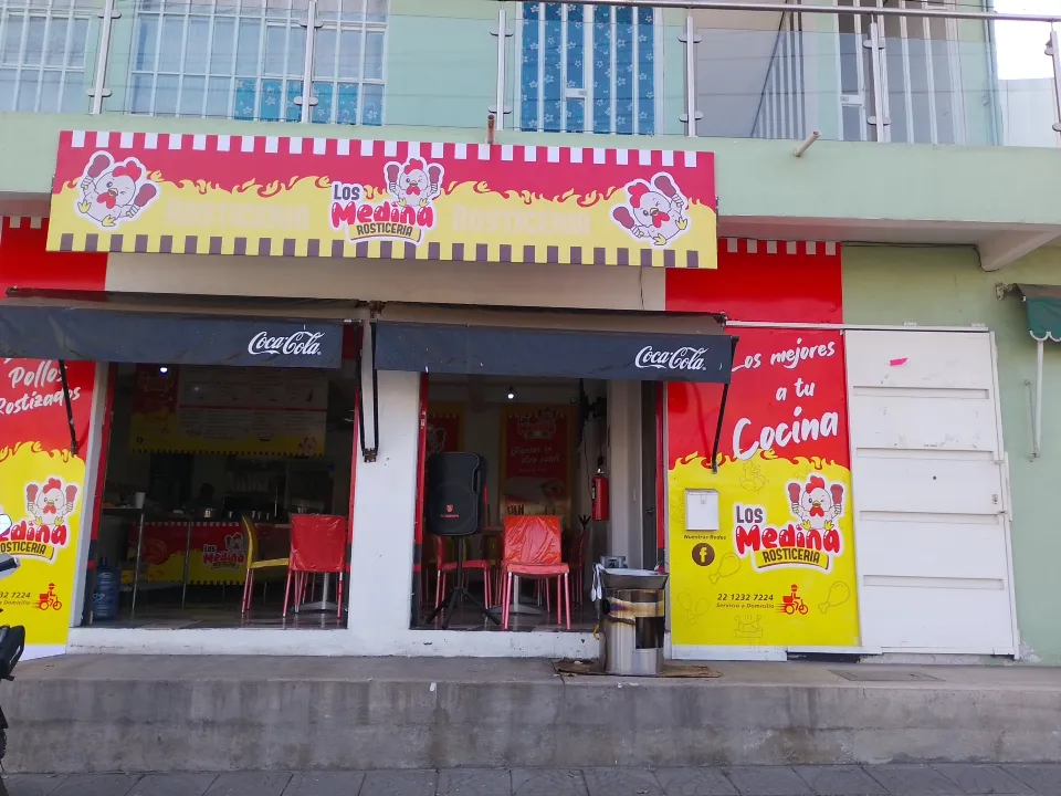 Fachada de Rosticería Los Medina con letrero rojo y amarillo y el comedor a la vista